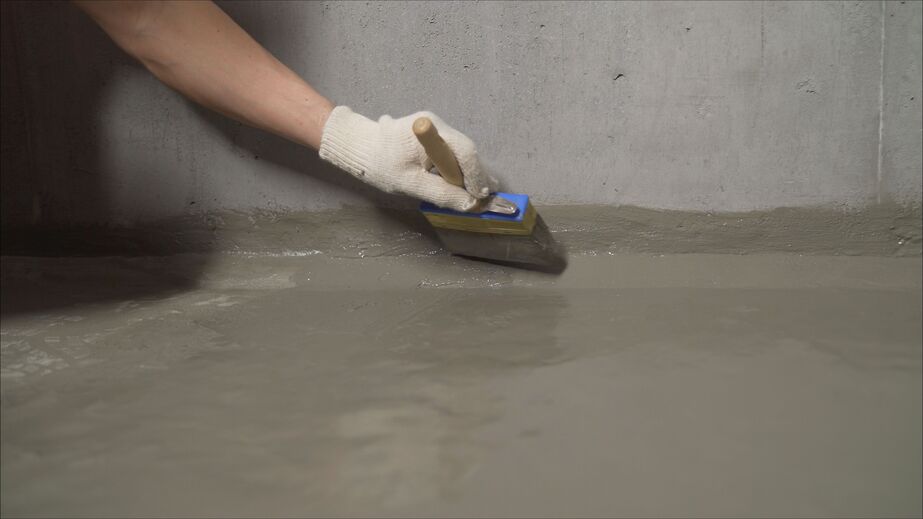 A Man waterproofs a basement floor with a brush